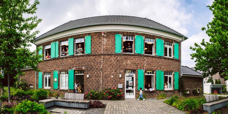 Das Ulla-Hahn-Haus von außen. Kinder gucken aus dem Fenster.